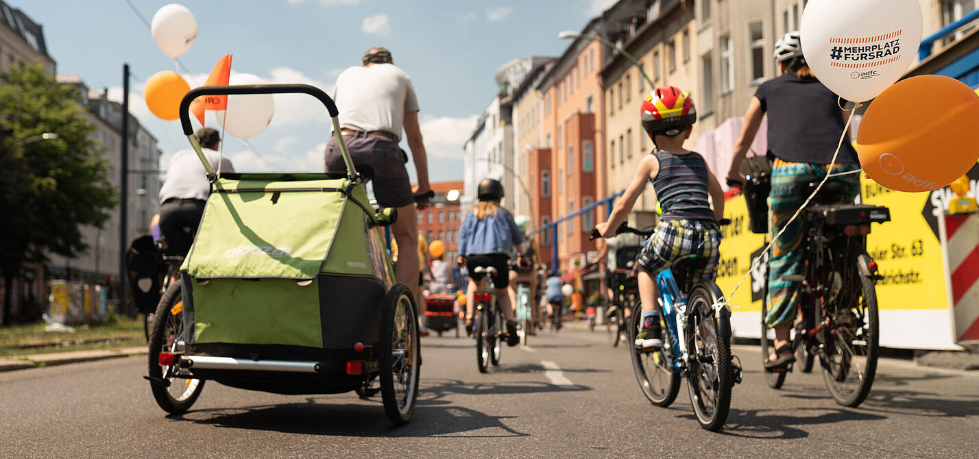 Familie bei Sternfahrt in Berlin Familie auf Rändern mit Fahrradanhänger auf städtischer Straße von hinten zu sehen